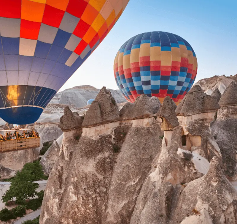 Kapadokya kaya oluşumları arasında sıcak hava balonları; görsel Göreme Açık Hava Müzesi içindeki bir kiliseyi göstermiyor