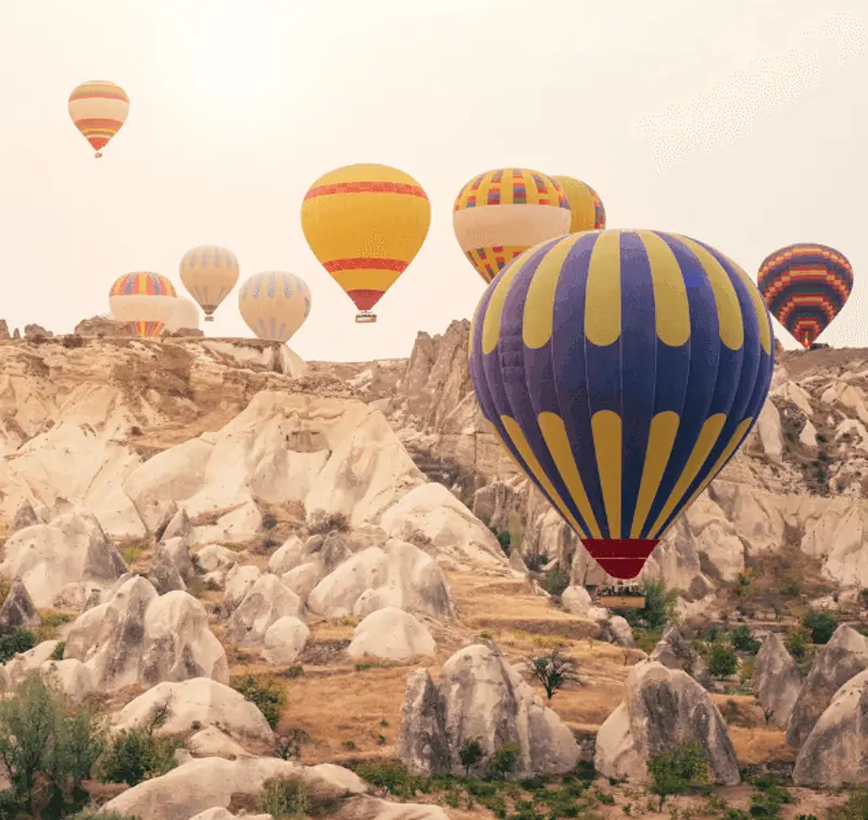 Kapadokya kaya oluşumlarının üzerinde sıcak hava balonları; görüntü belirli bir vadiyi göstermiyor