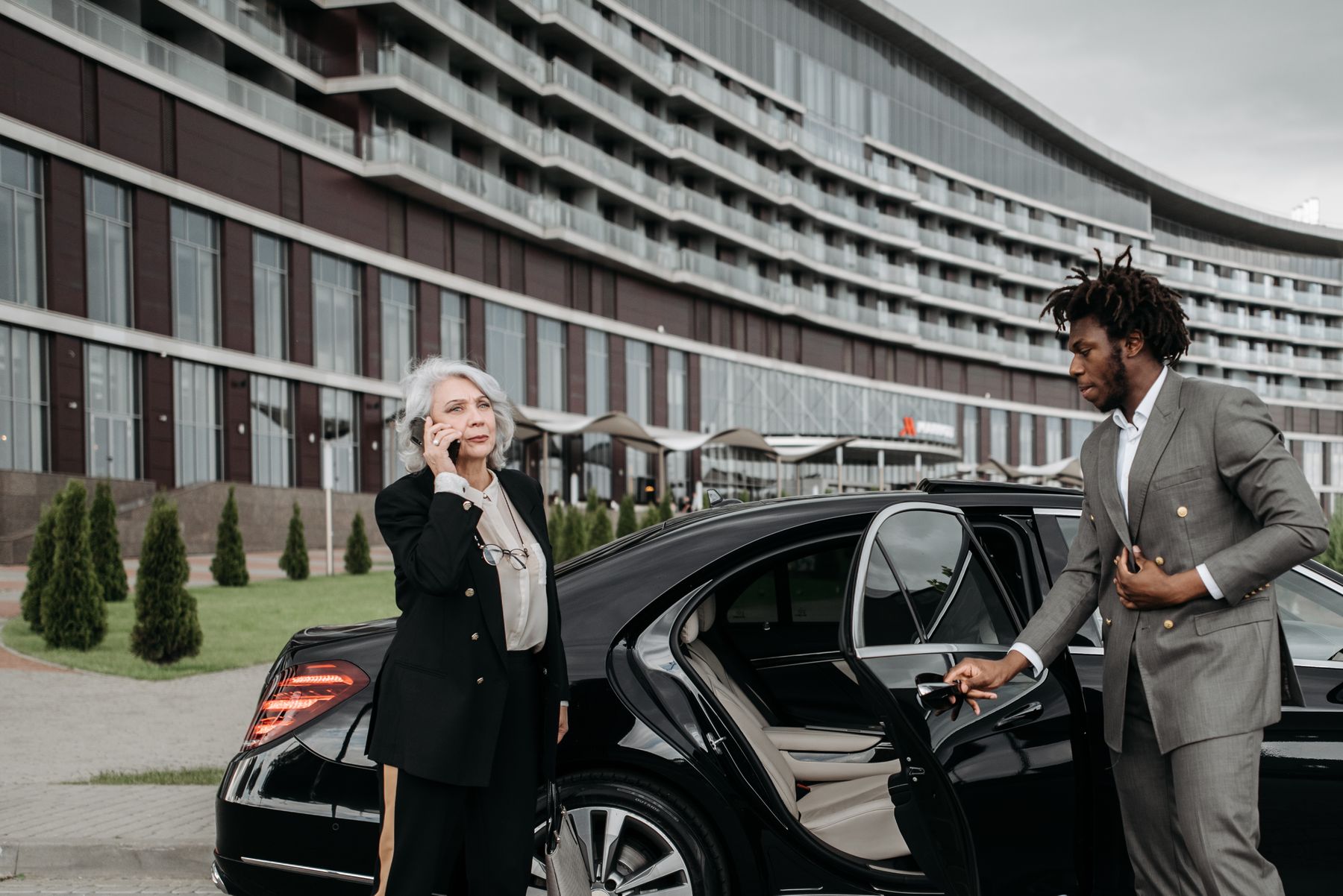 Chauffeur opening the rear door of a luxury car for a guest